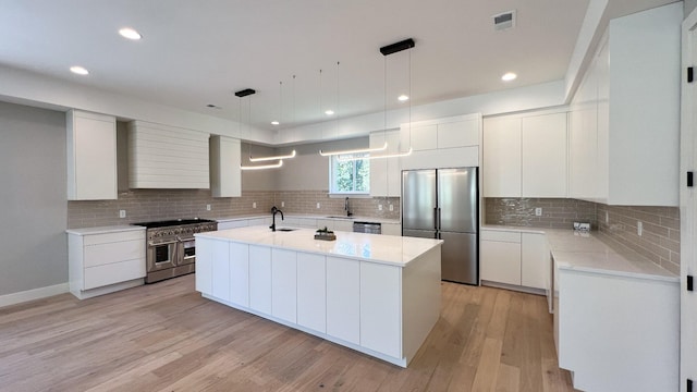 kitchen with light countertops, appliances with stainless steel finishes, a sink, and custom range hood