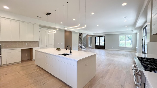 kitchen featuring light wood-type flooring, a sink, backsplash, and modern cabinets