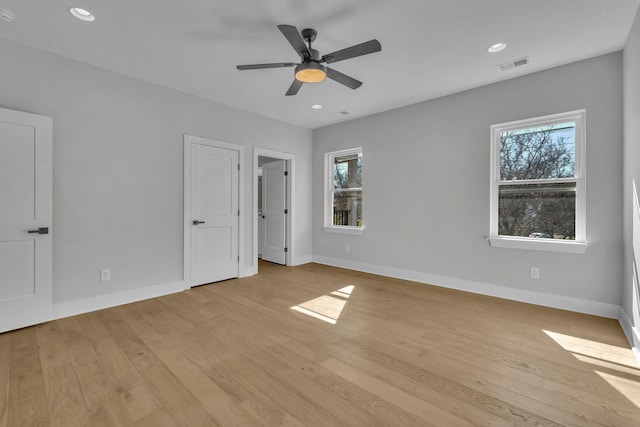 unfurnished bedroom with baseboards, multiple windows, visible vents, and light wood-style floors