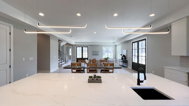 kitchen with recessed lighting, a sink, open floor plan, light wood-type flooring, and light stone countertops