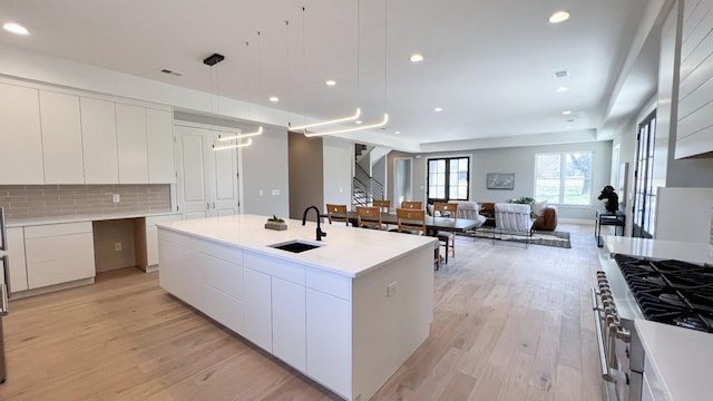 kitchen with light wood-type flooring, modern cabinets, open floor plan, and a sink