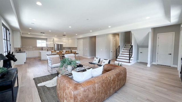 living area featuring light wood-style flooring, stairs, baseboards, and recessed lighting