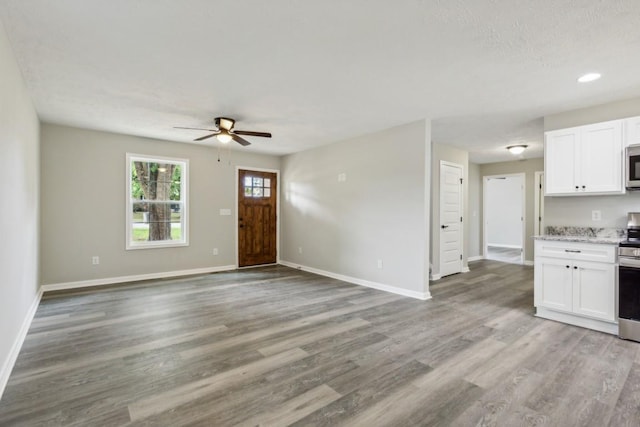 unfurnished living room with ceiling fan, a textured ceiling, and light hardwood / wood-style floors