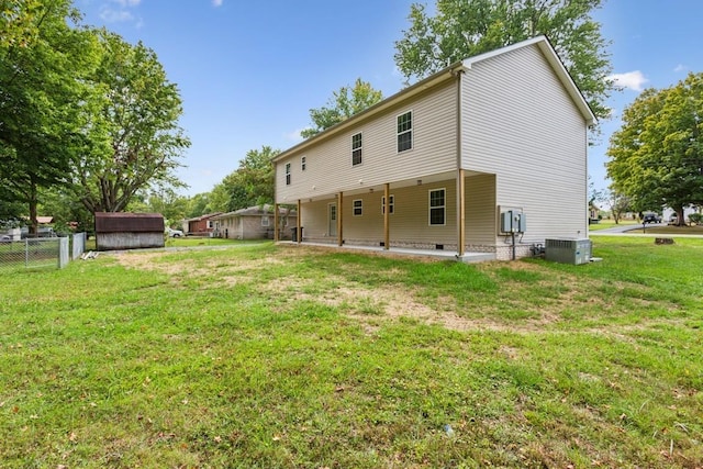 back of property with a lawn, central AC unit, and a storage shed