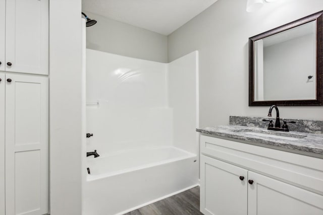 bathroom featuring wood-type flooring, vanity, and shower / washtub combination