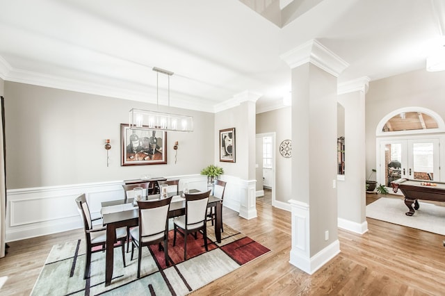 dining space featuring crown molding, decorative columns, french doors, and light wood-type flooring