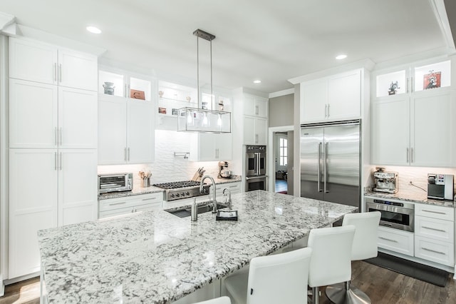 kitchen with stainless steel appliances, an island with sink, and white cabinets