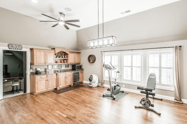 workout area featuring vaulted ceiling, sink, wine cooler, ceiling fan, and light hardwood / wood-style flooring