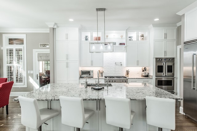 kitchen featuring a kitchen island with sink, hanging light fixtures, a breakfast bar area, and appliances with stainless steel finishes