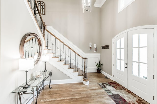 entryway featuring a high ceiling, a notable chandelier, french doors, and light hardwood / wood-style flooring