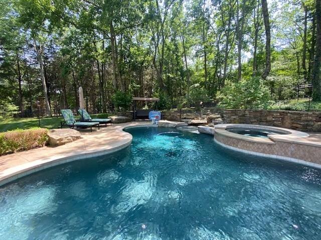 view of swimming pool featuring an in ground hot tub and a patio