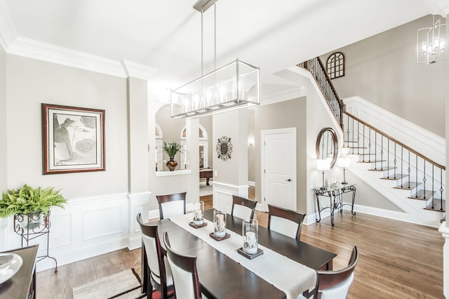 dining area with ornamental molding, light hardwood / wood-style flooring, and a notable chandelier