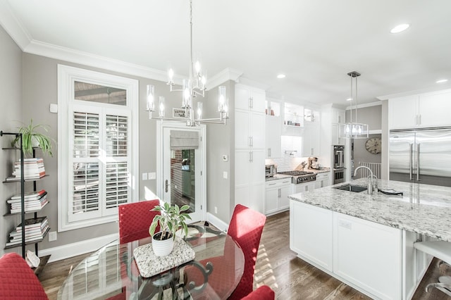 kitchen featuring light stone counters, a notable chandelier, decorative light fixtures, and white cabinets