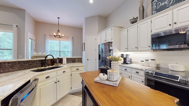 kitchen with a chandelier, sink, stainless steel appliances, and white cabinetry