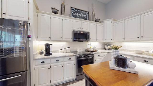 kitchen with white cabinets, appliances with stainless steel finishes, and light hardwood / wood-style flooring