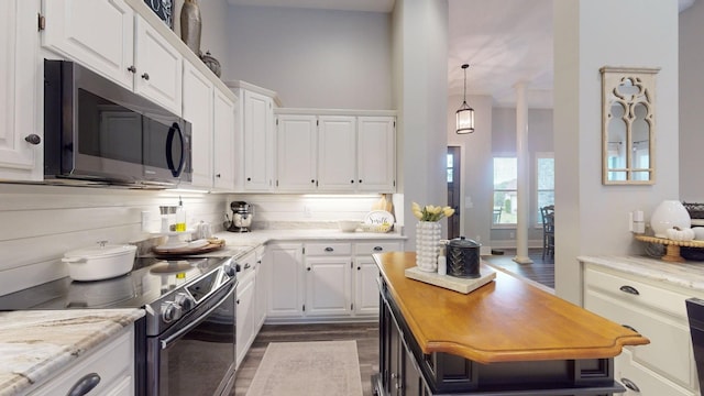 kitchen with white cabinetry, appliances with stainless steel finishes, decorative backsplash, dark hardwood / wood-style flooring, and light stone countertops