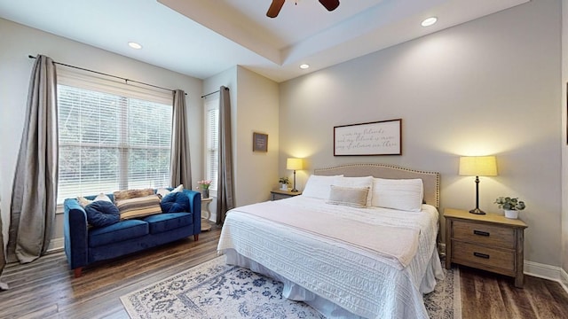 bedroom featuring ceiling fan, dark hardwood / wood-style flooring, and a tray ceiling