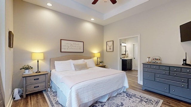 bedroom featuring ceiling fan, dark hardwood / wood-style floors, connected bathroom, and a raised ceiling