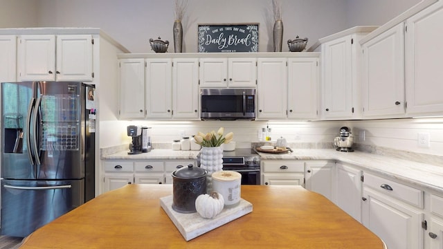 kitchen with white cabinets, backsplash, and appliances with stainless steel finishes