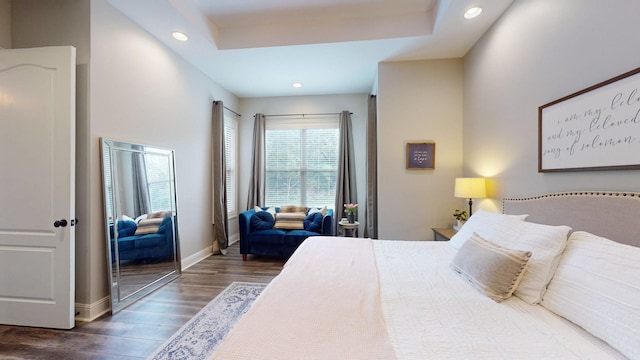 bedroom featuring dark hardwood / wood-style flooring and a tray ceiling