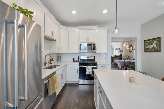 kitchen featuring white cabinets, appliances with stainless steel finishes, sink, backsplash, and hanging light fixtures