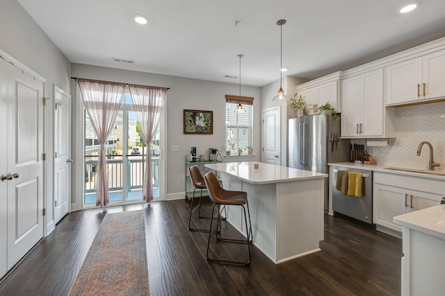 kitchen featuring pendant lighting, white cabinets, a center island, sink, and stainless steel dishwasher