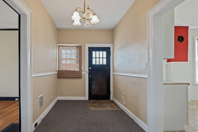 entrance foyer featuring a chandelier and carpet