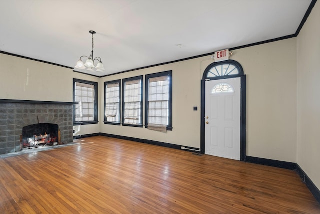 foyer entrance with hardwood / wood-style flooring, crown molding, and a stone fireplace