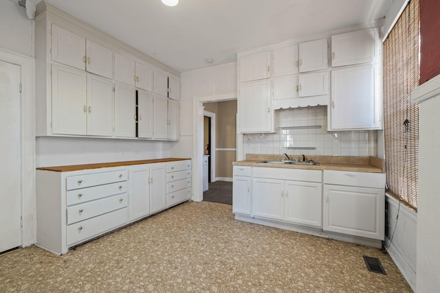 kitchen featuring sink, white cabinetry, and backsplash