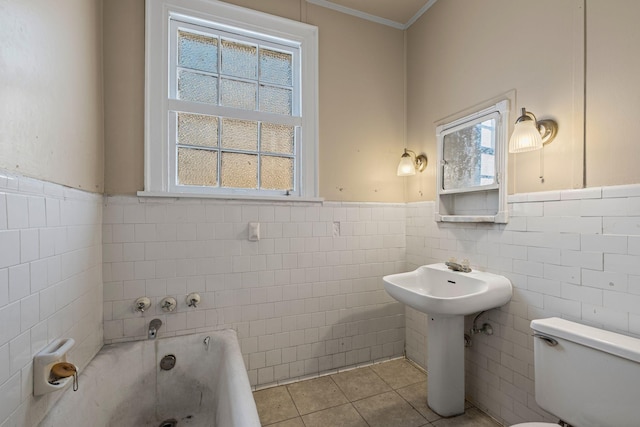 bathroom with tile patterned flooring, tile walls, a bathtub, toilet, and crown molding