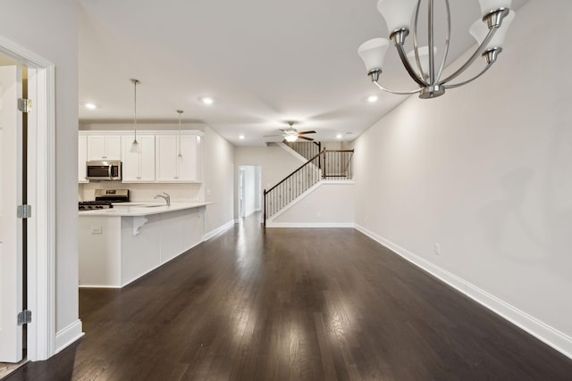 kitchen featuring decorative light fixtures, a breakfast bar, kitchen peninsula, stainless steel appliances, and white cabinets