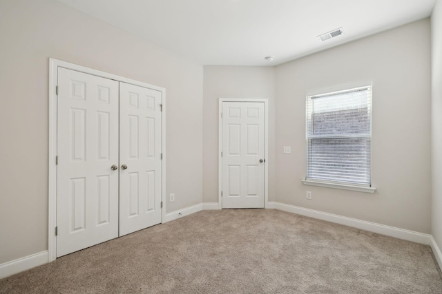 unfurnished bedroom featuring a closet and light colored carpet