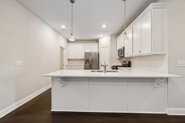 kitchen featuring pendant lighting, appliances with stainless steel finishes, white cabinets, sink, and a breakfast bar