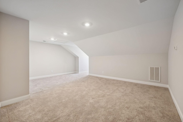 additional living space featuring light colored carpet and vaulted ceiling