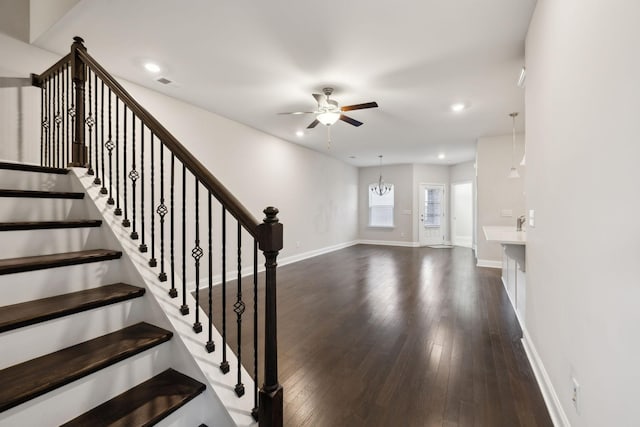 entryway featuring dark wood-type flooring and ceiling fan with notable chandelier