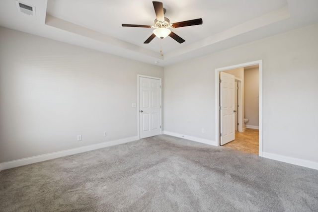 carpeted spare room with ceiling fan and a tray ceiling