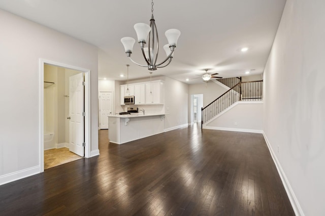 unfurnished living room with dark wood-type flooring, sink, and ceiling fan with notable chandelier