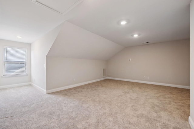 additional living space featuring light carpet and vaulted ceiling