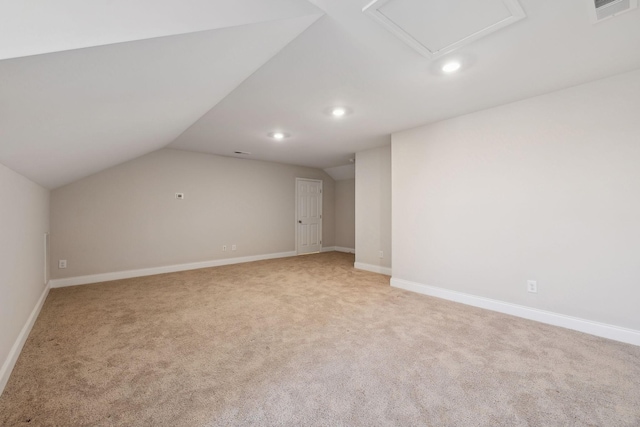 additional living space featuring light colored carpet and vaulted ceiling