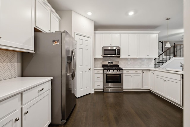 kitchen with appliances with stainless steel finishes, decorative backsplash, white cabinetry, and hanging light fixtures