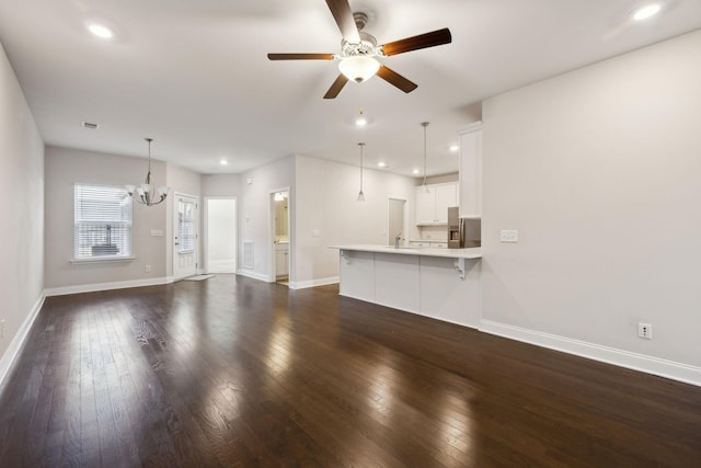 unfurnished living room with ceiling fan with notable chandelier, sink, and dark hardwood / wood-style flooring