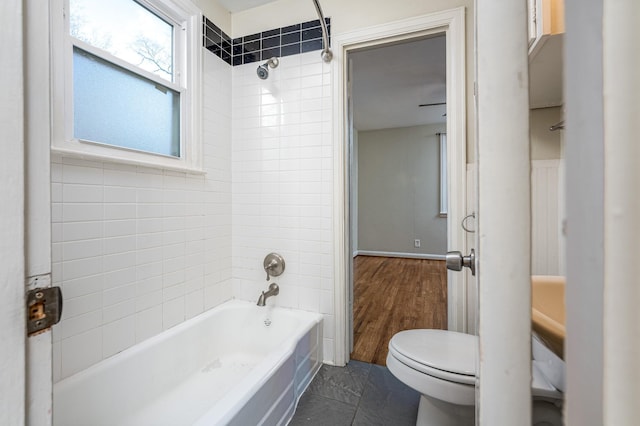 bathroom featuring toilet, tiled shower / bath, and tile patterned floors