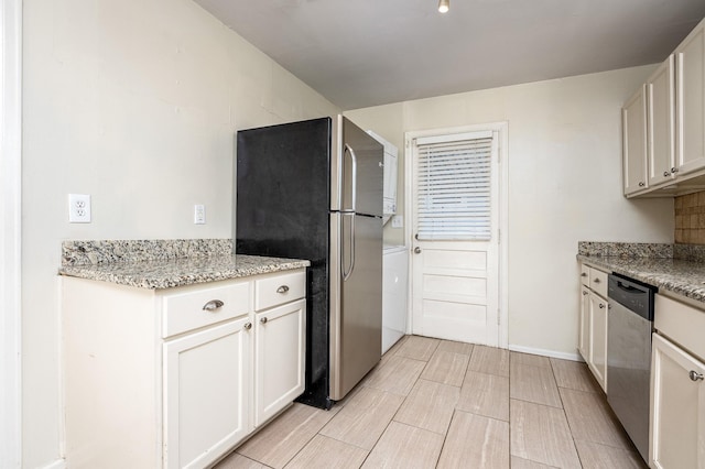 kitchen featuring light stone countertops, stainless steel appliances, and white cabinetry