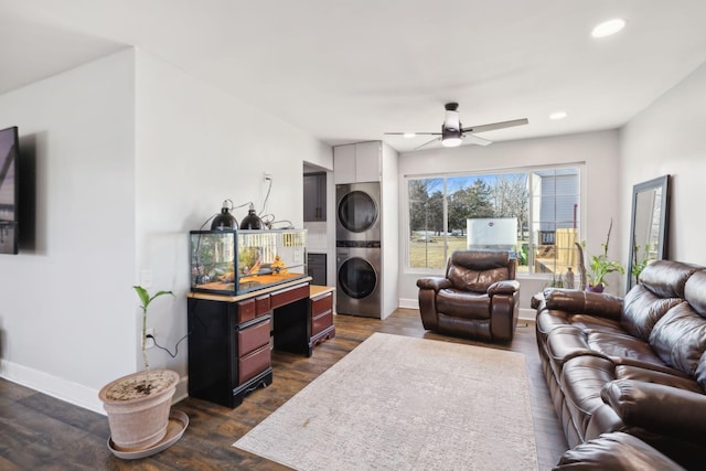 living room with stacked washing maching and dryer, dark wood-type flooring, and ceiling fan