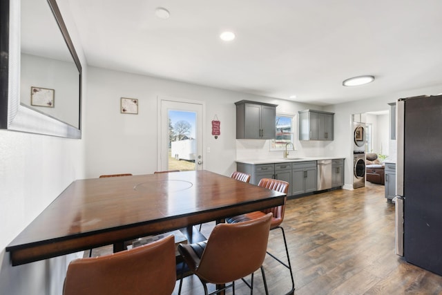 dining area with stacked washing maching and dryer, dark hardwood / wood-style flooring, and sink