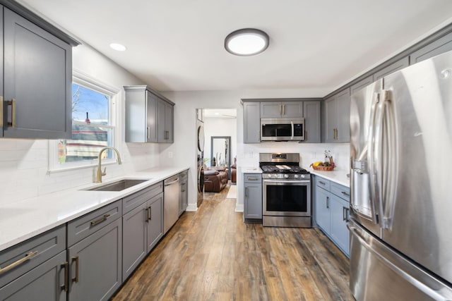 kitchen with appliances with stainless steel finishes, sink, dark hardwood / wood-style flooring, and gray cabinets