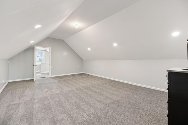 bonus room with light colored carpet and vaulted ceiling