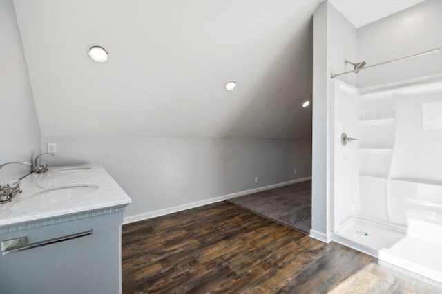 bathroom with vaulted ceiling, a shower, hardwood / wood-style flooring, and vanity