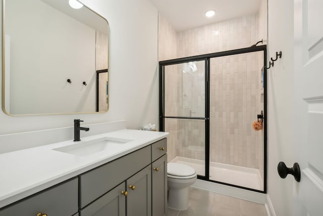 bathroom featuring tile patterned floors, toilet, a shower with shower door, and vanity