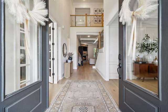 foyer with ornamental molding, plenty of natural light, light hardwood / wood-style floors, and a fireplace